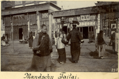 Menschen in traditioneller Kleidung auf einer Straße in Mandschu Taitai, China, während des frühen 20. Jahrhunderts