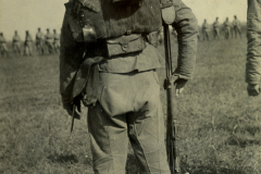 Chinesischer Soldat in Uniform beobachtet eine Militärübung auf offenem Feld aus der Rückansicht