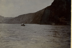 Ruderboot auf dem Wasser in Jehol, China, umgeben von felsiger Küste und sanften Hügeln