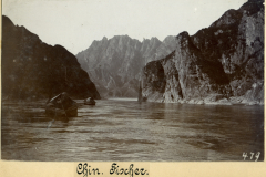 Fischer in China bei Sonnenaufgang auf einem ruhigen Fluss umgeben von majestätischen Bergen