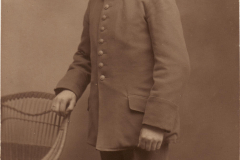Ein Soldat in Uniform steht an einem Stuhl in einem Studio von 1910