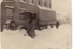 Menschen schaufeln Schnee vor einem Lkw in einer verschneiten Straße
