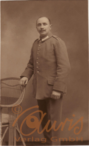 Ein Soldat in Uniform steht an einem Stuhl in einem Studio von 1910