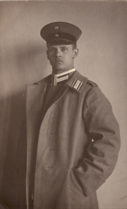 Ein historischer Soldat in Uniform mit einem Mantel und Mütze vor einer Wand