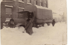 Menschen schaufeln Schnee vor einem Lkw in einer verschneiten Straße