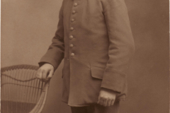 Ein Soldat in Uniform steht an einem Stuhl in einem Studio von 1910