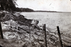 Mann am Ufer eines Gewässers mit Drahtzaun in der Natur