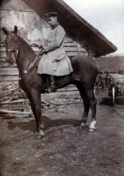 Ein Soldat auf einem Pferd vor einem Holzgebäude in ländlicher Umgebung