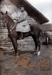 Ein Soldat auf einem Pferd vor einem Holzgebäude in ländlicher Umgebung