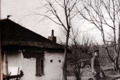 Ein Soldat steht vor einem alten Haus in ländlicher Umgebung im Frühling
