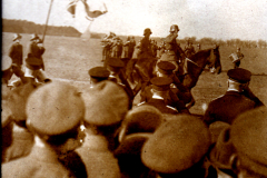Historische Militärparade mit Reiter und Flaggen in weitläufiger Landschaft
