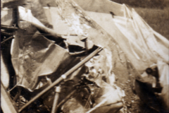 Überreste eines beschädigten Flugzeugs auf einem Feld in ländlicher Umgebung