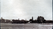 Grünes Feld mit Bäumen und einem kleinen Gebäude in der Ferne im Morgengrauen