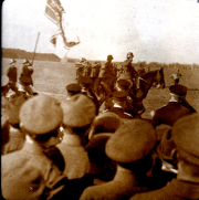 Historische Militärparade mit Reiter und Flaggen in weitläufiger Landschaft
