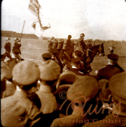 Historische Militärparade mit Reiter und Flaggen in weitläufiger Landschaft
