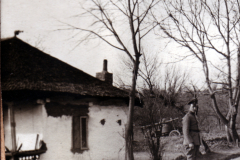 Ein Soldat steht vor einem alten Haus in ländlicher Umgebung im Frühling