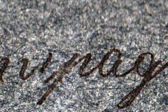 Detailaufnahme eines kalligrafischen Schriftzugs auf grauem Hintergrund