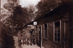 Historisches Bild einer Gruppe von Menschen vor einer Baracke im Wald