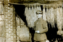 Ein Soldat steht mit einer Zigarette vor einer Backsteinmauer in einem Dorf