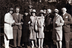 Eine Gruppe von neun Personen kleidet sich stilvoll im Park der 1920er Jahre