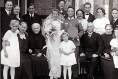 Hochzeitsfeier einer Familie in den 1940er Jahren vor einem Backsteinhaus
