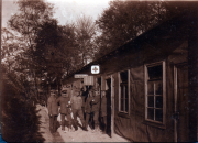 Historisches Bild einer Gruppe von Menschen vor einer Baracke im Wald
