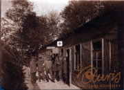 Historisches Bild einer Gruppe von Menschen vor einer Baracke im Wald