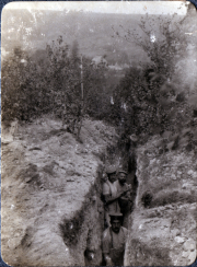 Zwei Soldaten stehen in einem Schützengraben, umgeben von Erde und Vegetation
