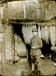Ein Soldat steht mit einer Zigarette vor einer Backsteinmauer in einem Dorf