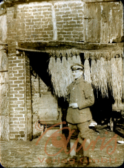 Ein Soldat steht mit einer Zigarette vor einer Backsteinmauer in einem Dorf