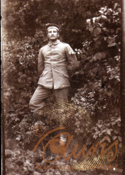 Ein Soldat in Uniform steht vor einer grünen Wand aus Pflanzen im Freien