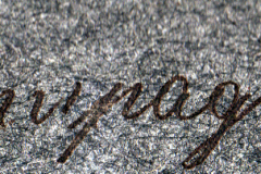 Detailaufnahme eines kalligrafischen Schriftzugs auf grauem Hintergrund