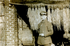 Ein Soldat steht mit einer Zigarette vor einer Backsteinmauer in einem Dorf