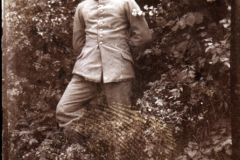 Ein Soldat in Uniform steht vor einer grünen Wand aus Pflanzen im Freien