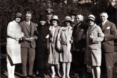 Eine Gruppe von neun Personen kleidet sich stilvoll im Park der 1920er Jahre
