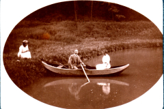 Zwei Personen rudern in einem Boot auf einem ruhigen Gewässer im Wald