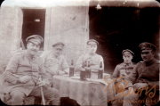 Vier Soldaten in Uniform sitzen an einem Tisch mit Bierflaschen vor einem Gebäude während des Ersten Weltkriegs