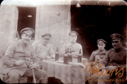 Vier Soldaten in Uniform sitzen an einem Tisch mit Bierflaschen vor einem Gebäude während des Ersten Weltkriegs