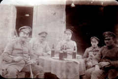 Vier Soldaten in Uniform sitzen an einem Tisch mit Bierflaschen vor einem Gebäude während des Ersten Weltkriegs