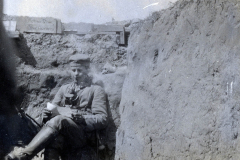 Soldat sitzt entspannt in einem Schützengraben an der Westfront während des Ersten Weltkriegs