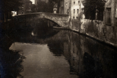 Eine ruhige Szene am Kanal in Brügge zeigt historische Gebäude und eine Steinbrücke