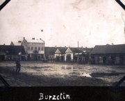 Eine historische Ansicht von Burzctin mit Gebäuden und einer staubigen Fläche
