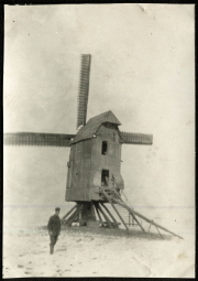 Historische Windmühle mit einem Landarbeiter im Vordergrund in einem landwirtschaftlichen Umfeld