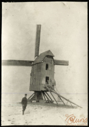 Historische Windmühle mit einem Landarbeiter im Vordergrund in einem landwirtschaftlichen Umfeld