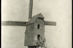 Historische Windmühle mit einem Landarbeiter im Vordergrund in einem landwirtschaftlichen Umfeld