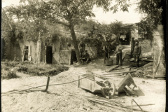 Arbeiter im Freien neben einer Ruine mit Werkzeug und Baum im Hintergrund