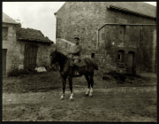 Soldat auf einem Pferd vor einer alten Steinhütte in ländlicher Umgebung