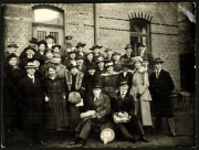 Gruppenaufnahme von Männern und Frauen in historischen Outfits vor einem Backsteingebäude
