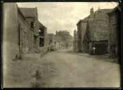 Ruine eines kleinen Dorfes nach dem Krieg, mit beschädigten Gebäuden und einer leeren Straße