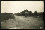 Eine ländliche Straße mit einem Haus und einer Person auf dem Boden in der Nähe eines beschaulichen Gebiets